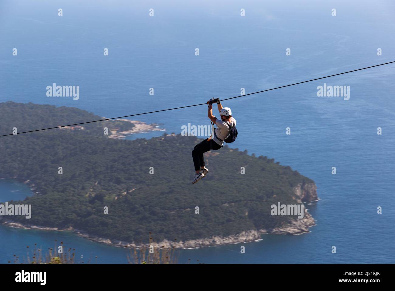 Man going down on rope above Adriatic sea. Adventure attraction near Dubrovnik. Croatia. Stock Photo