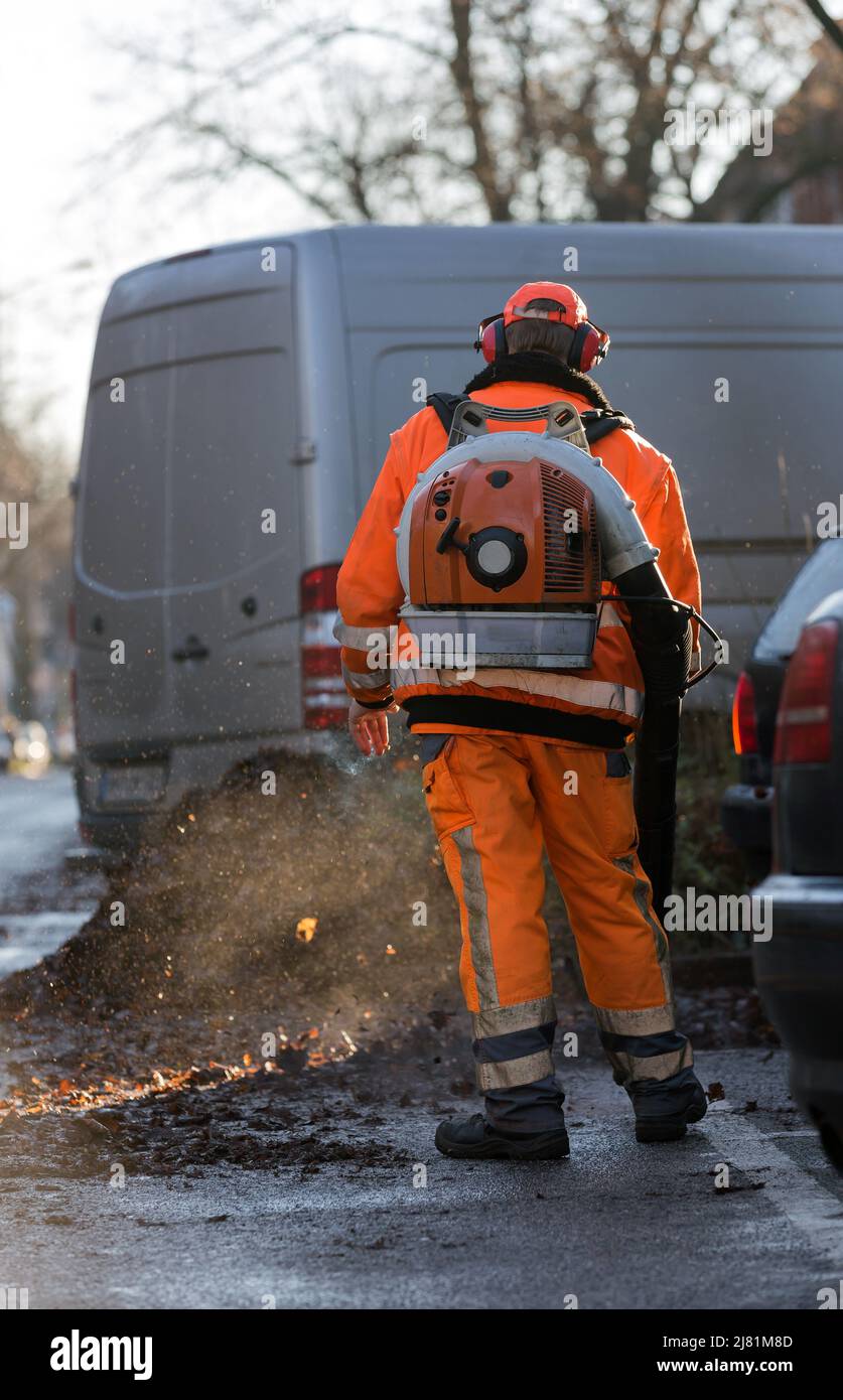 worker with leaf blower cleans the street Stock Photo