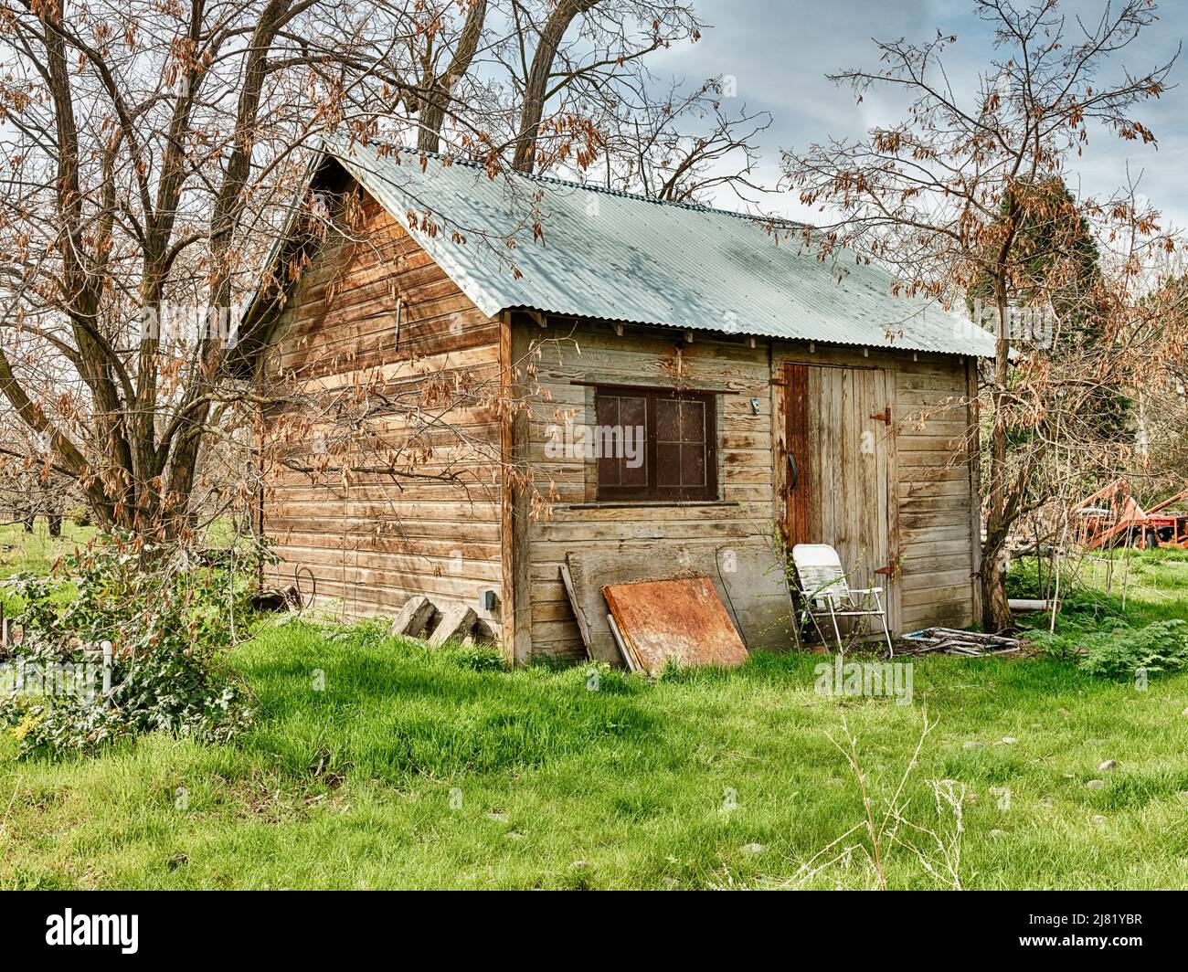 In a rural scene near the Oregon In The Rocks AVA, a white folding chair sits outside a small farm outbuilding. Stock Photo