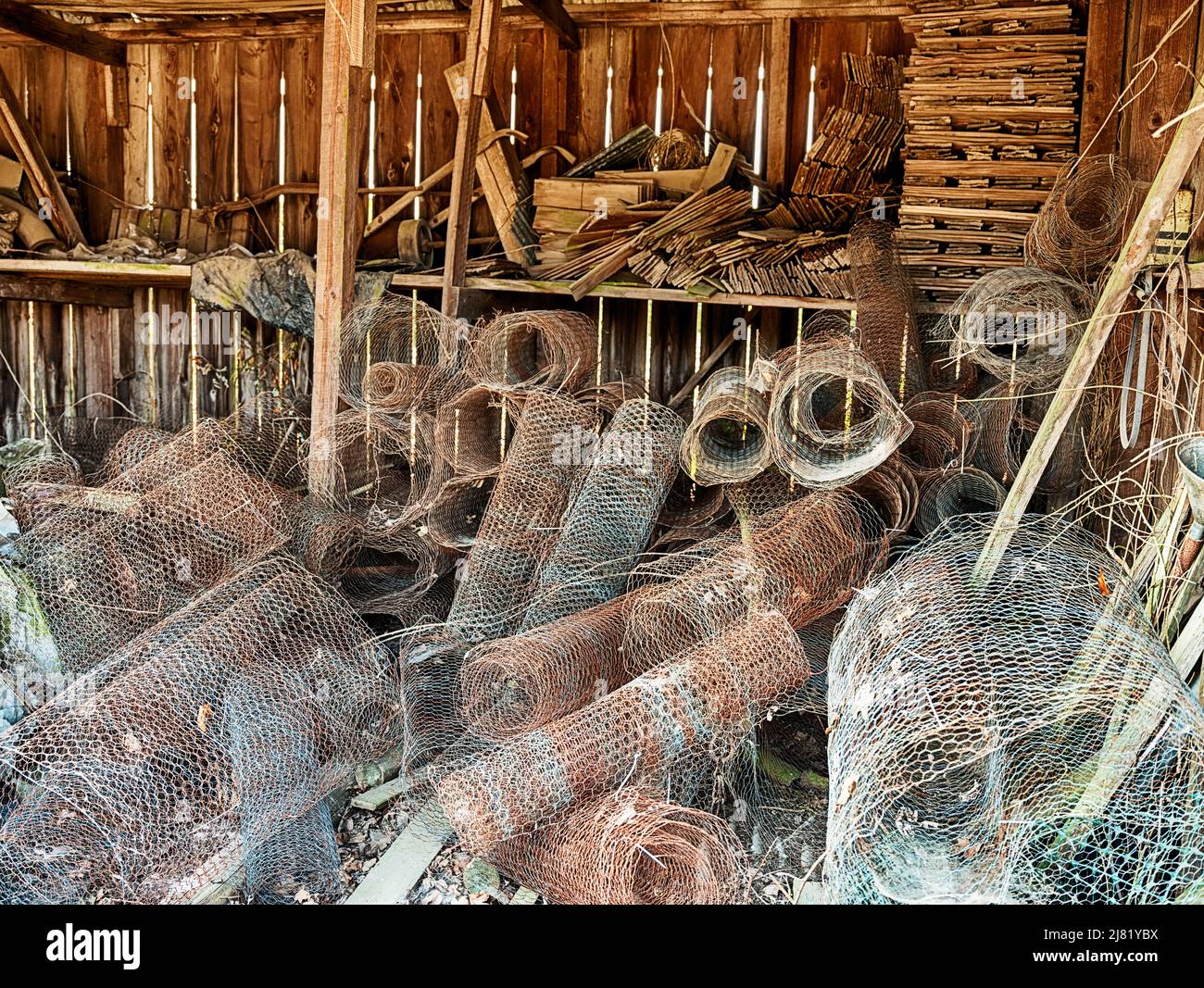 Rolls of rusting fencing material fill an old wood barn in Oregon. Stock Photo
