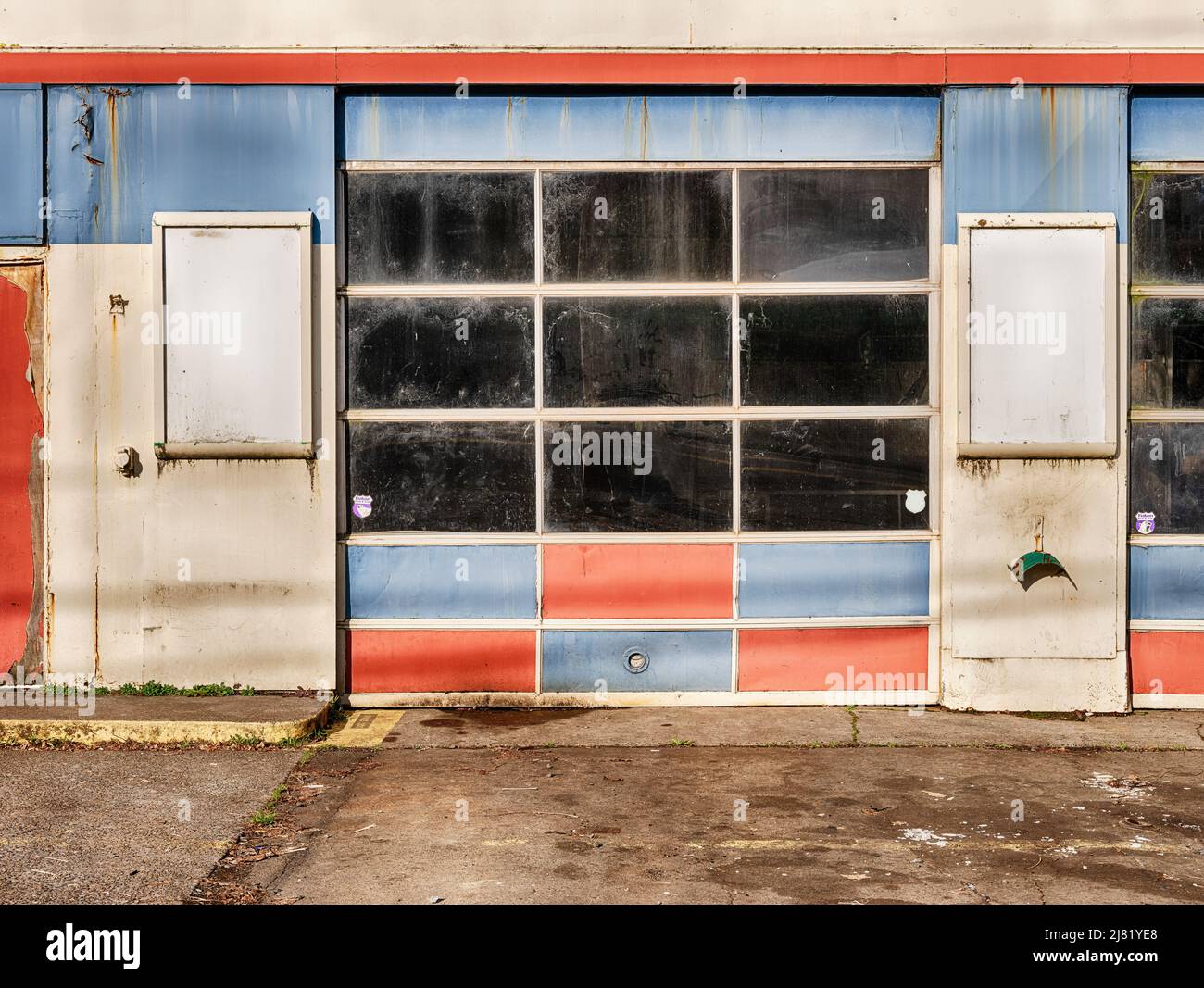 Service station is closed but still shows faded blue and red garage doors. Stock Photo