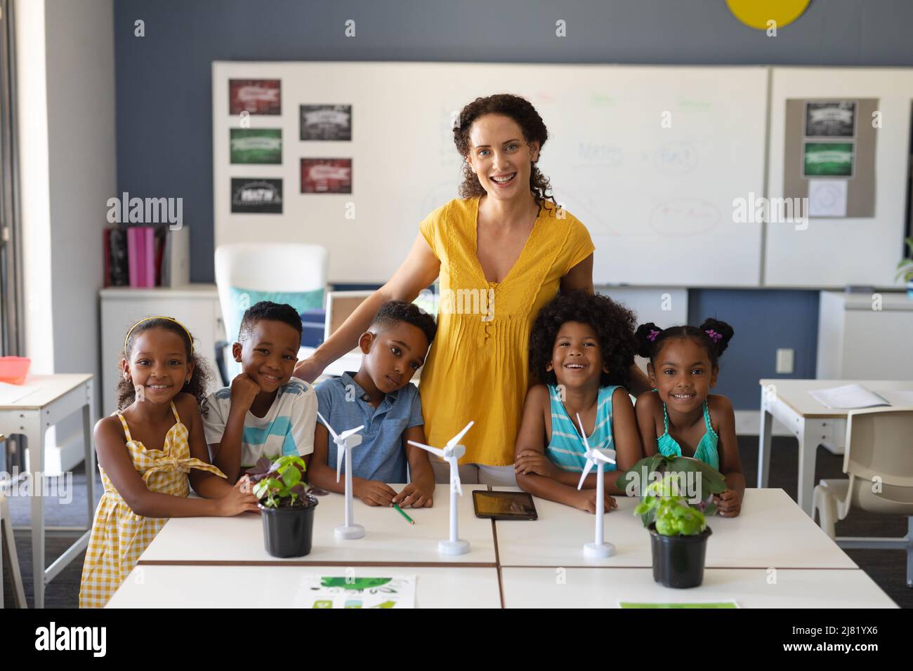 Portrait of happy african american students with caucasian young female teacher with windmill models Stock Photo