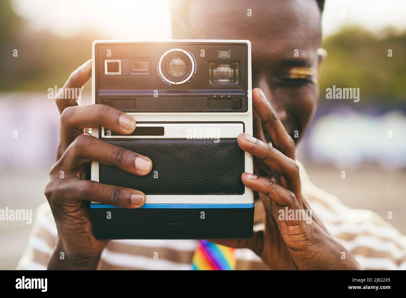 Young gay african man using vintage old camera outdoor - Focus on hands Stock Photo