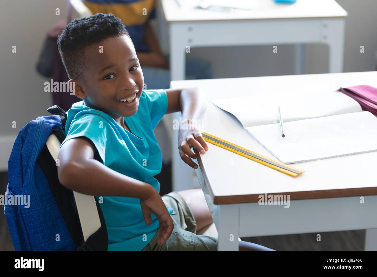 Portrait of smiling african american elementary schoolboy sitting on ...