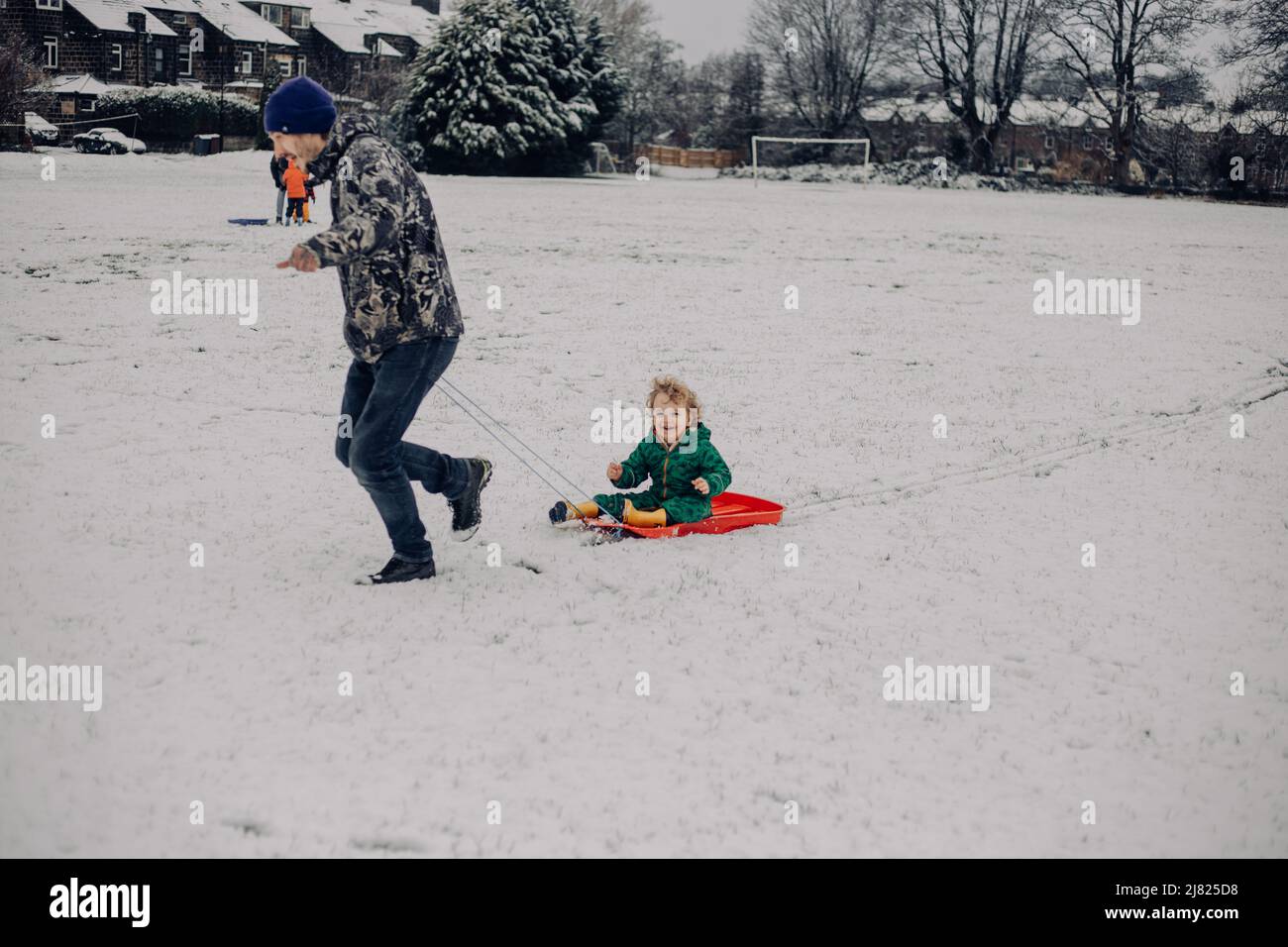 Happy Child family sledging in the snow UK Stock Photo - Alamy