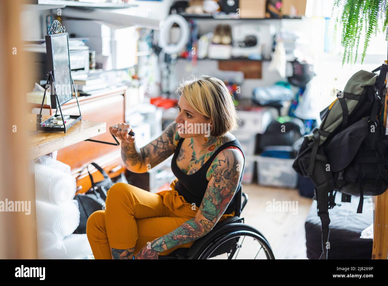 Portrait of an young tattooed woman in a wheelchair at home Stock Photo