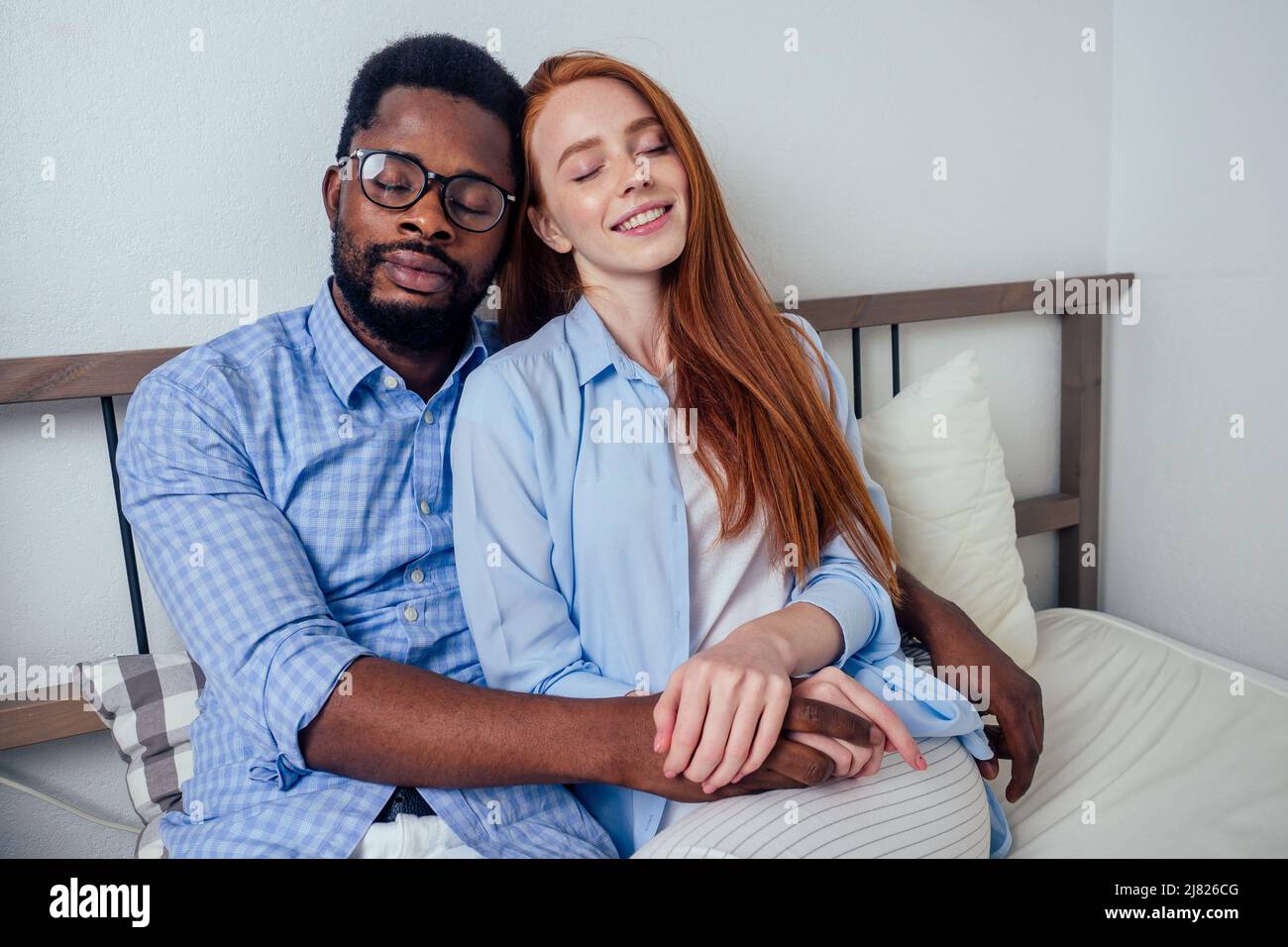 redhaired ginger caucasian happy female and multi-ethnic afro man together  lying in bed bedroom.lifestyle tolerance concept Stock Photo - Alamy