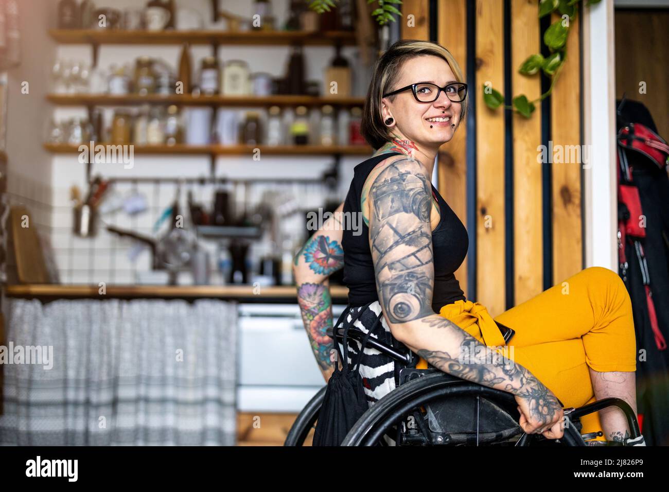 Portrait of an young tattooed woman in a wheelchair at home Stock Photo