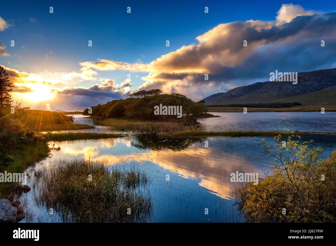 Sun setting over a lake in a mountain landscape, Derryclare Lake, Connemara, County Galway, Ireland Stock Photo