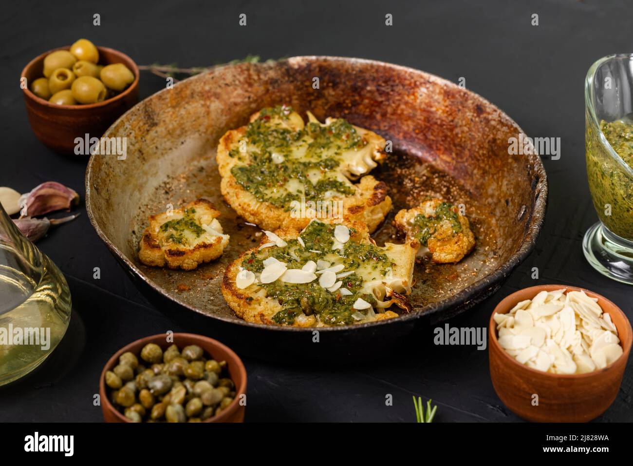 Cauliflower steak with spices lies in a frying pan. Olive oil