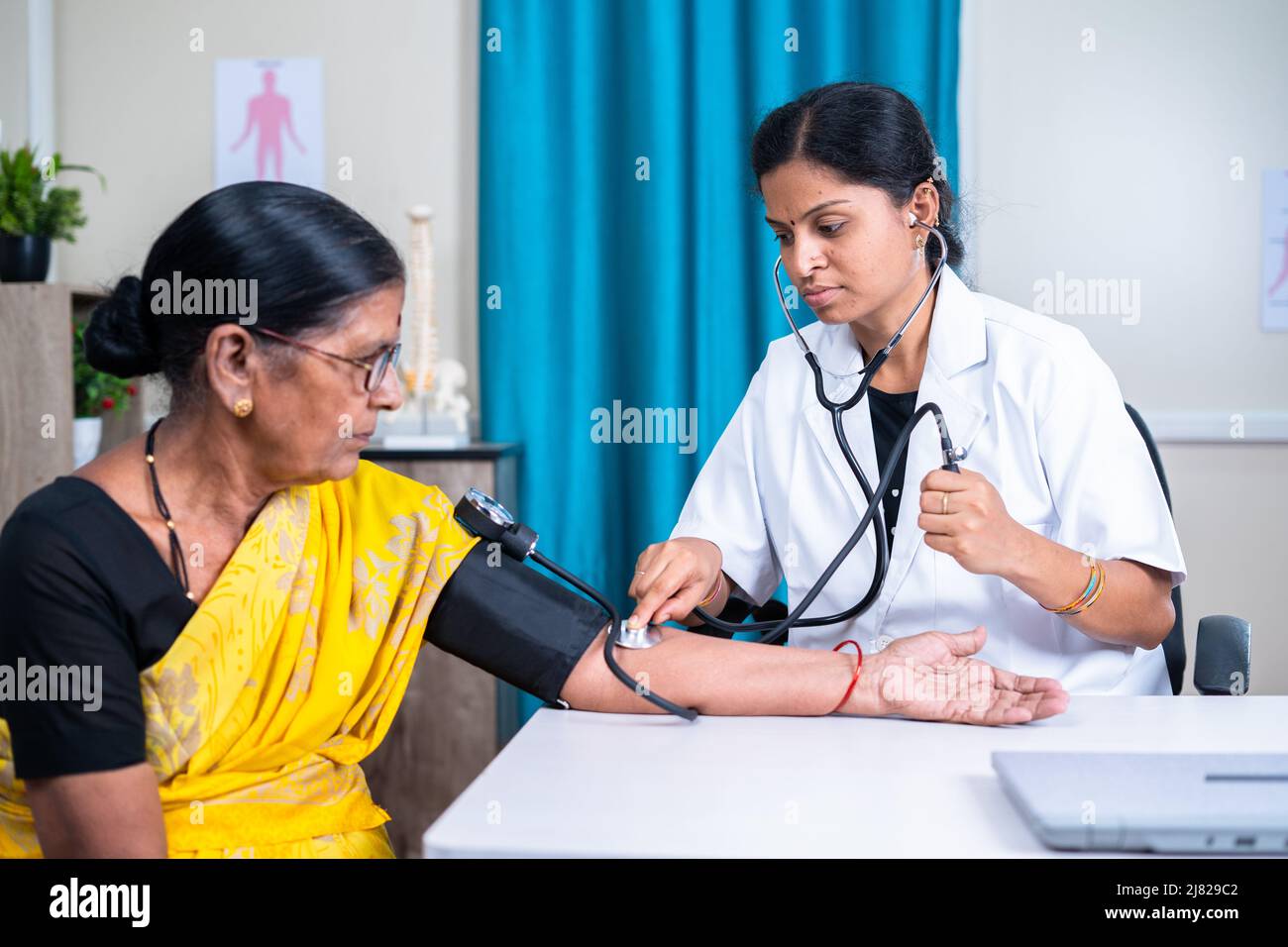 Doctor checking blood pressure or bp of senior woman patient at hospital - concept of health care, medical treatment and consultation. Stock Photo