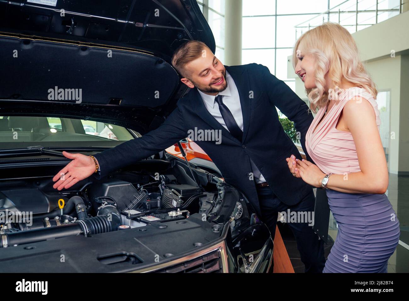 salesman in suit showing catalog to female blonde customer in dealership salon Stock Photo