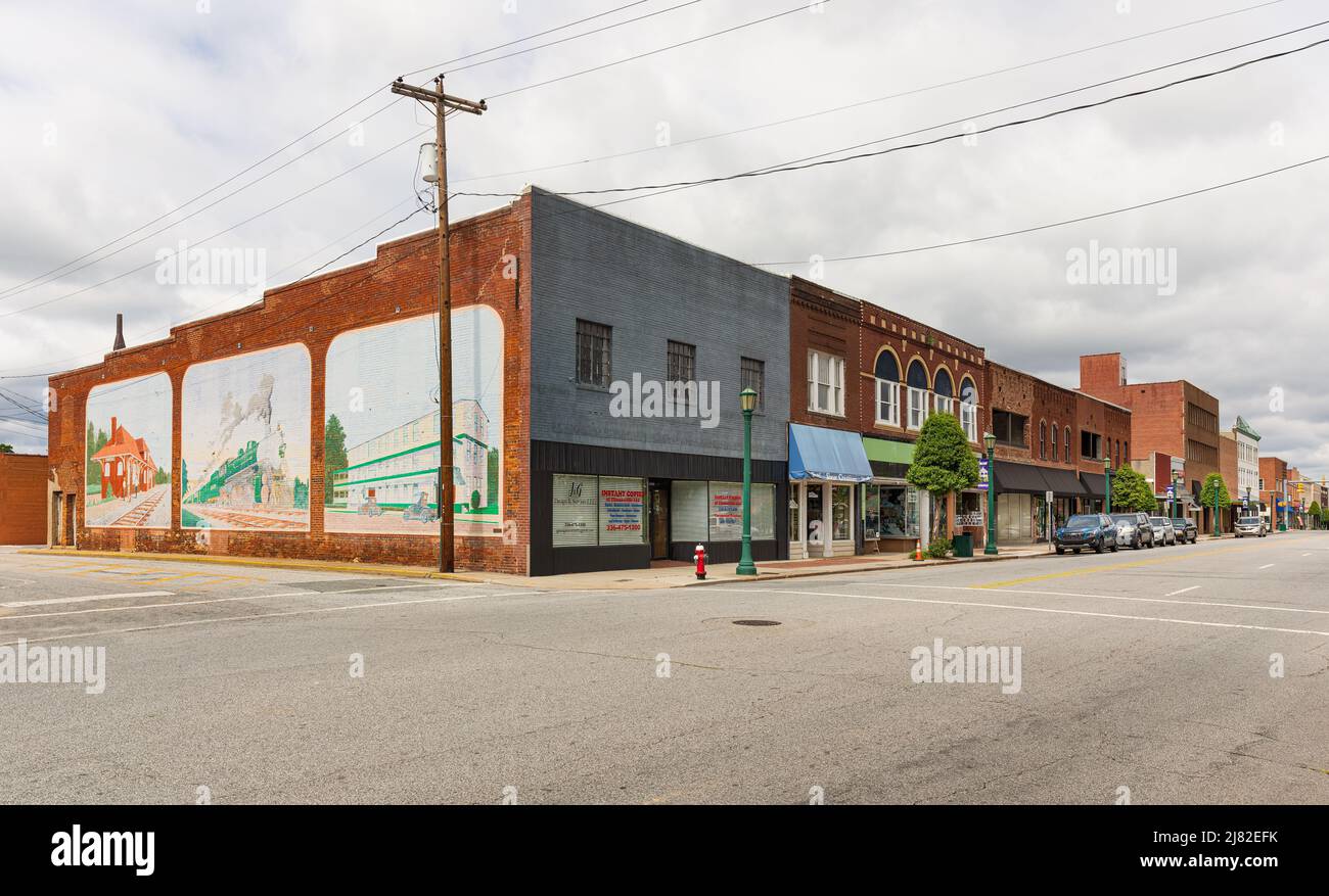 THOMASVILLE, NC, USA-8 MAY 2022: Main Street, diagonal view of buildings, mural of historic scenes on end wall. Stock Photo