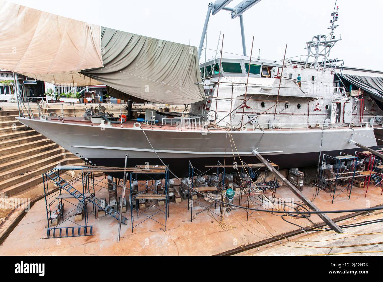 A patrol vessel or military vessel building in a dry dock at a naval shipyard. Stock Photo