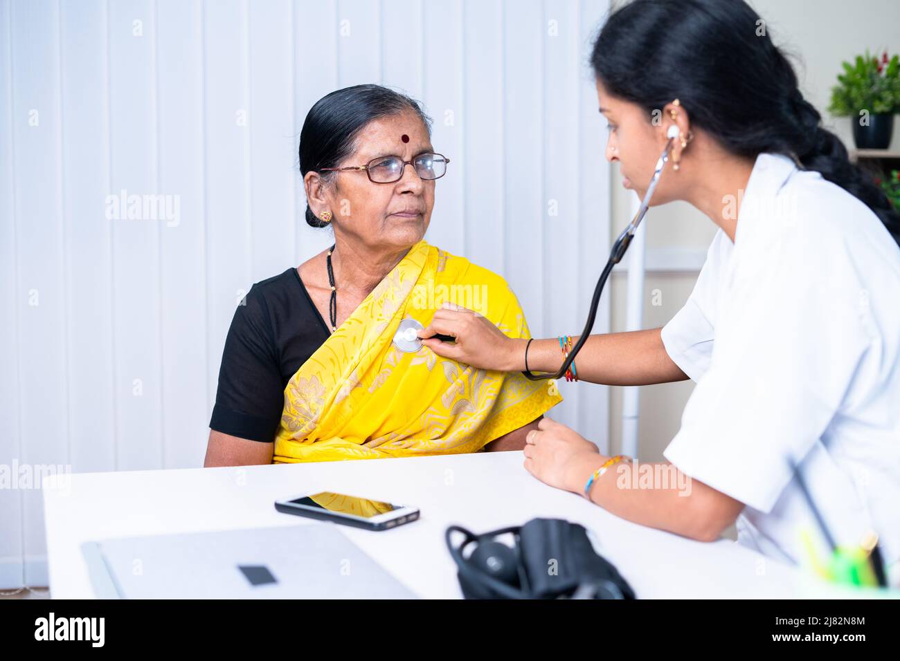 doctor examining health of senior sick patient at hospital - concept of treatment, routine checkup and healthcare. Stock Photo