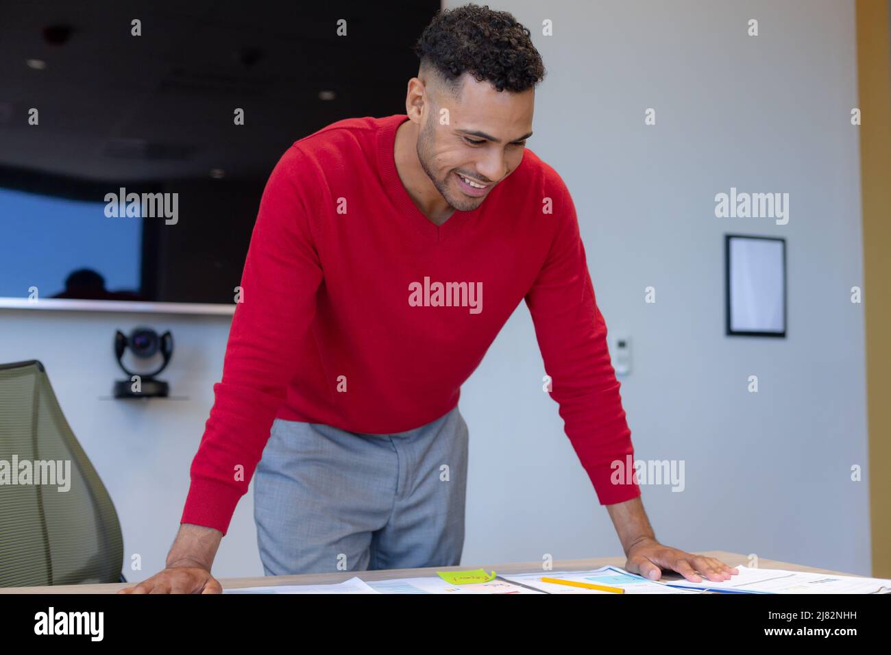 Happy hispanic young male advisor leaning on desk working at modern workplace Stock Photo