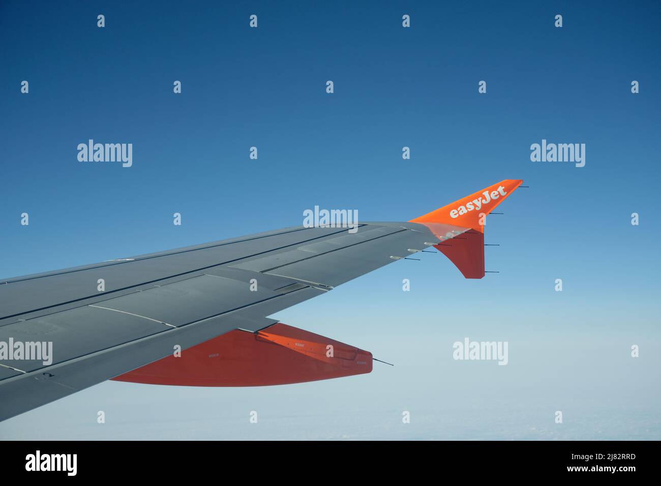 The view from an Easyjet aircraft of the wing and blue sky beyond. Stock Photo