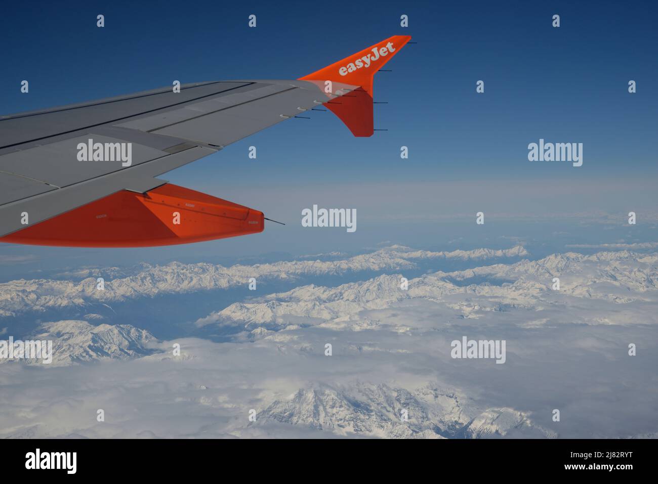 View from a aircraft window of an EasyJet wing and the European Alps below. Stock Photo