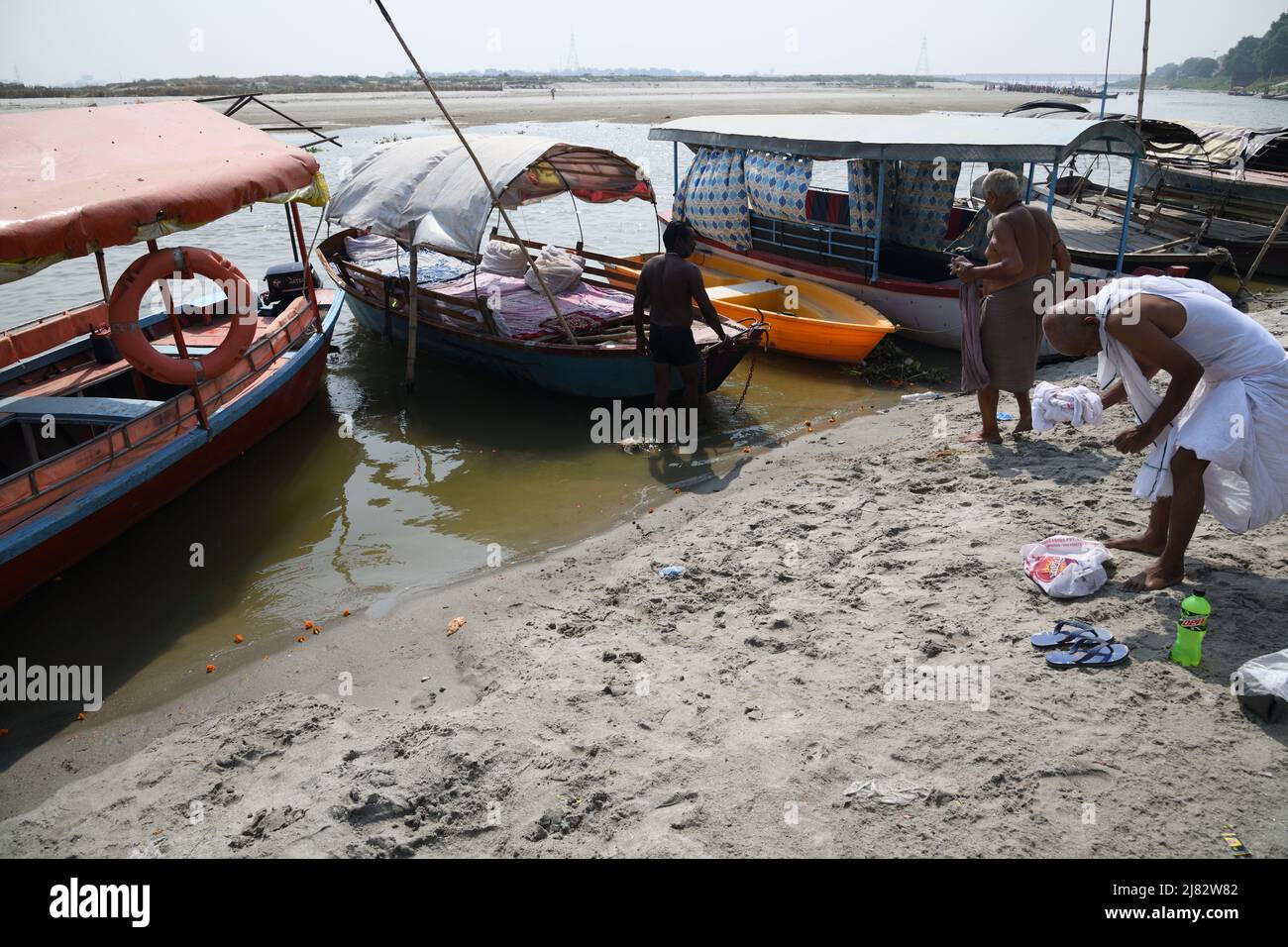 Floating desi boats in shallow riverbed of the holy Ganges in scorching
