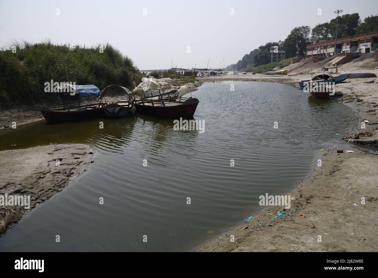 Floating desi boats in shallow riverbed of the holy Ganges in scorching