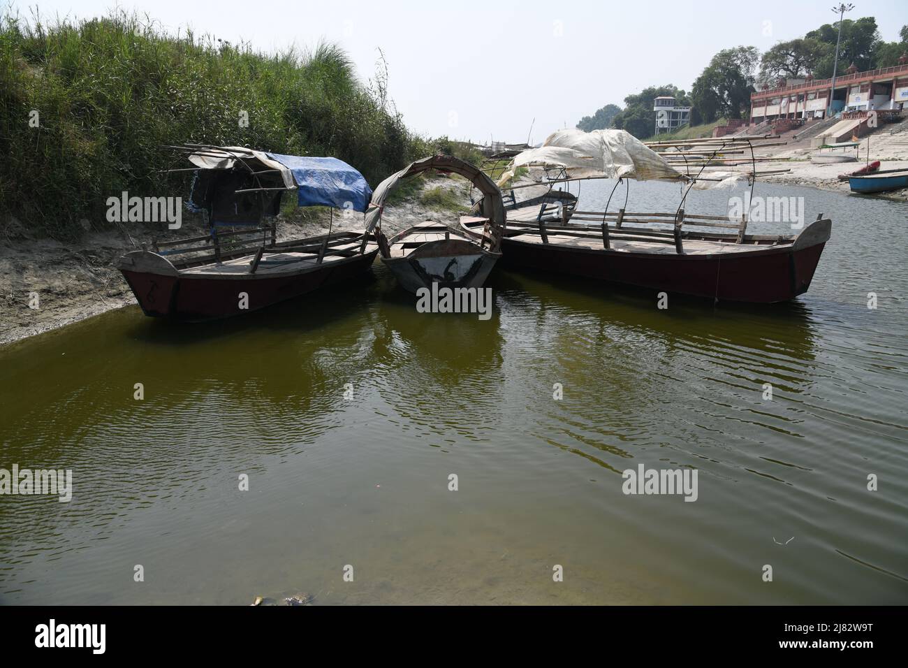 Floating desi boats in shallow riverbed of the holy Ganges in scorching