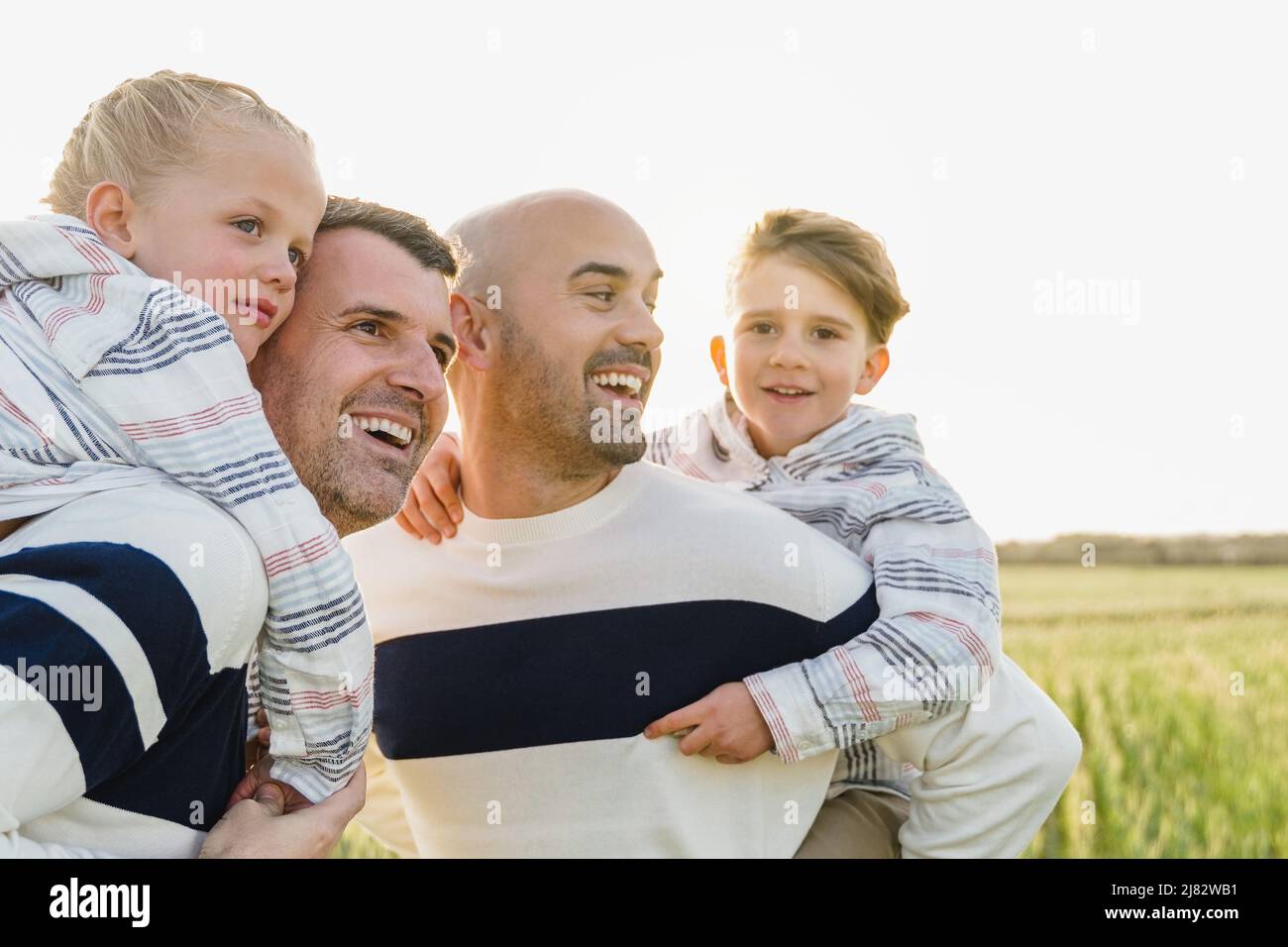 Gay male parents having fun with their sons outdoor in summer day - LGBT diversity family concept - Focus on left child face Stock Photo