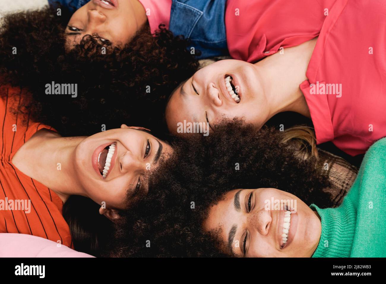 Multiethnic female friends having fun lying together in circle - Focus on right Hispanic girl Stock Photo