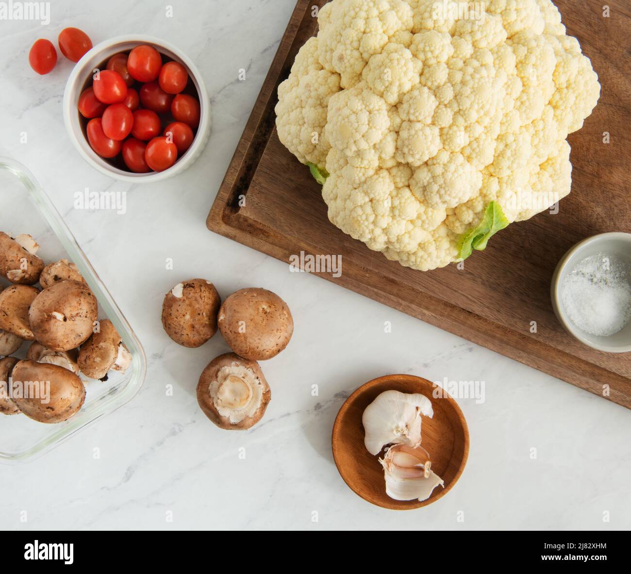 Cooking scene with Cauliflower, mushrooms, garlic, and tomatoes Stock Photo
