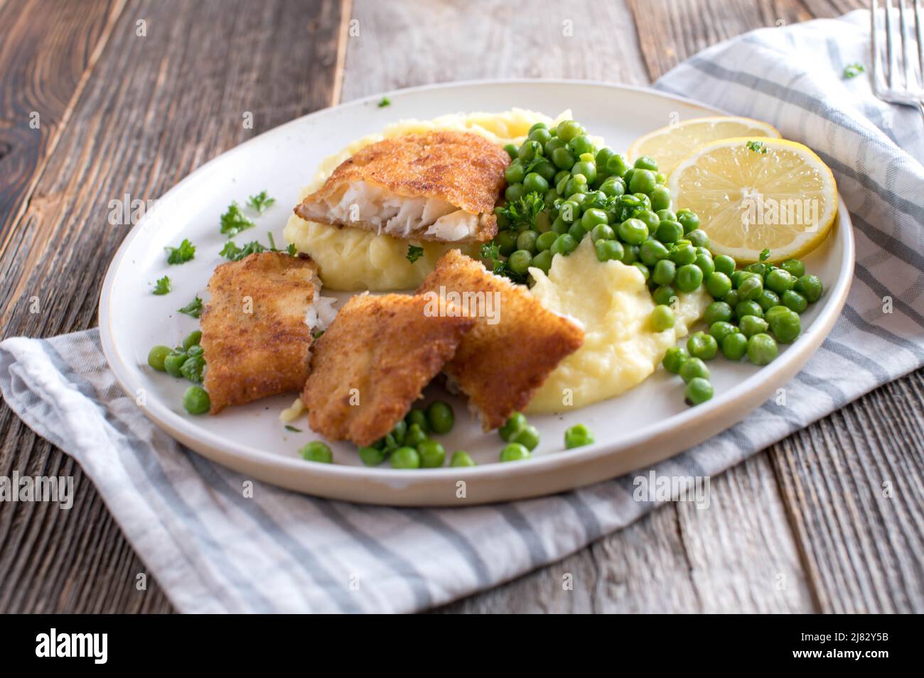 Breaded redfish with mashed potatoes and green peas on a plate Stock Photo