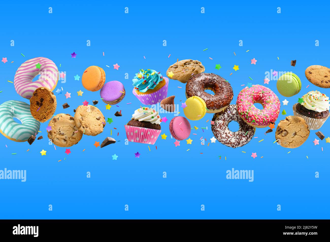 Donuts, cupcakes, cookies, macarons flying on blue background. Stock Photo