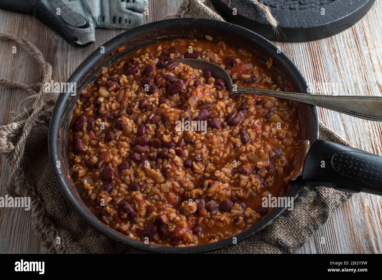 Fitness meal with brown rice, kidney beans, vegetable and tomato sauce. Served in a frying pan on wooden table Stock Photo