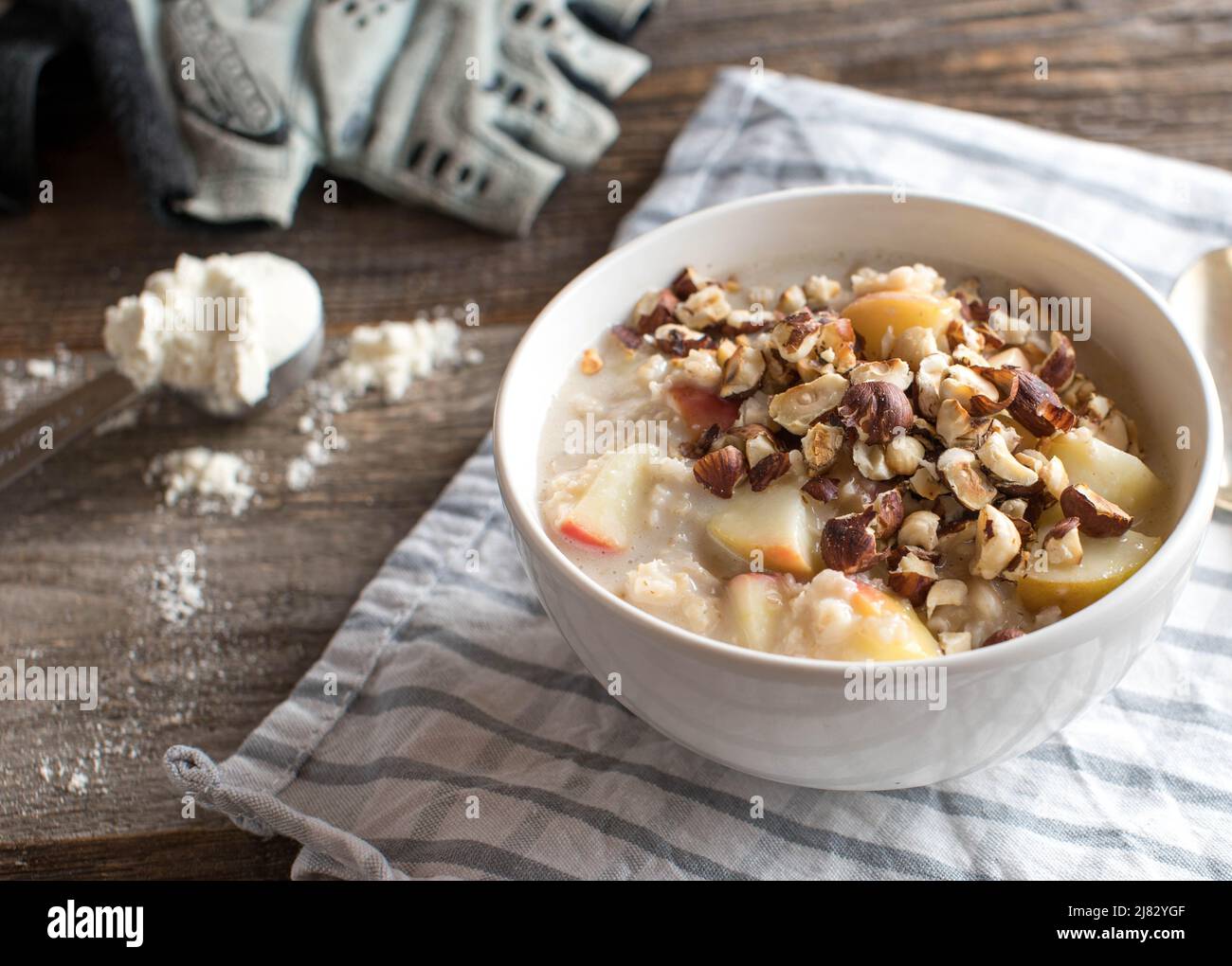 Protein breakfast bowl with porridge. Cooked with whey protein powder and apples. Served with roasted hazelnuts Stock Photo