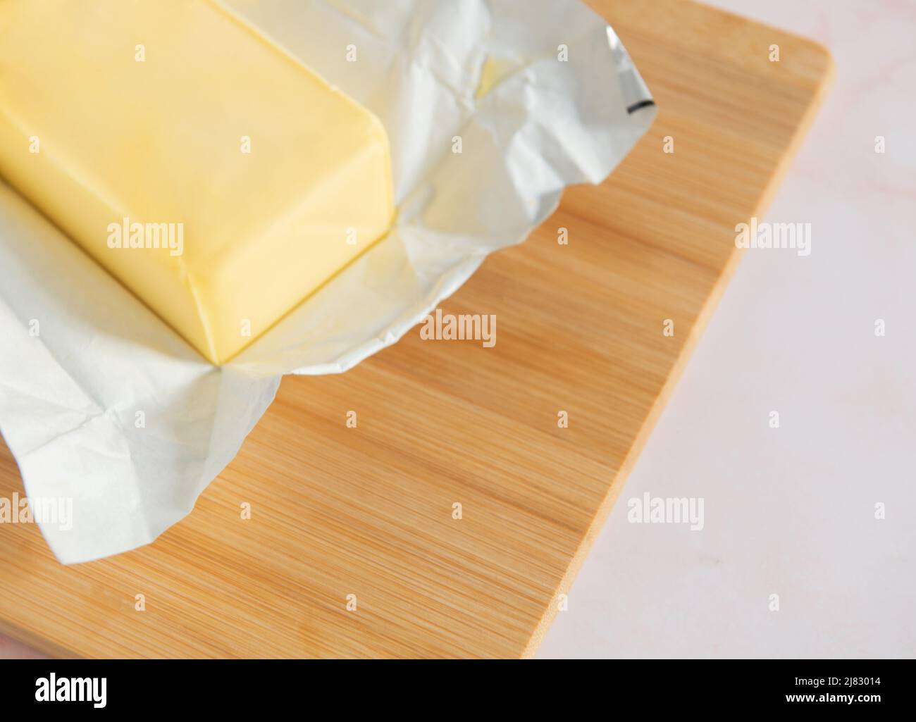 Cutting board with a block of butter unwrapped Stock Photo