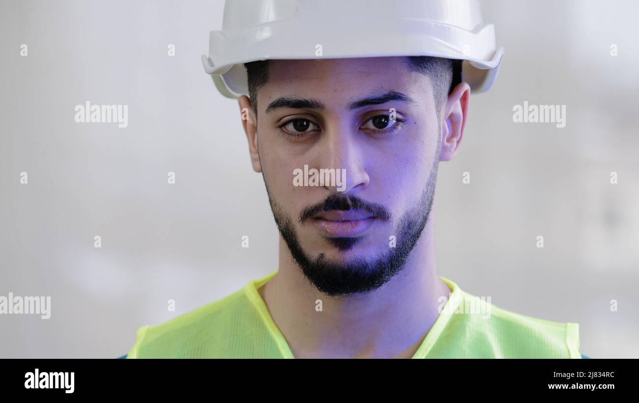 Close-up portrait serious hispanic man contractor mechanic male builder wear special uniform safety helmet looking at camera confident arabian Stock Photo