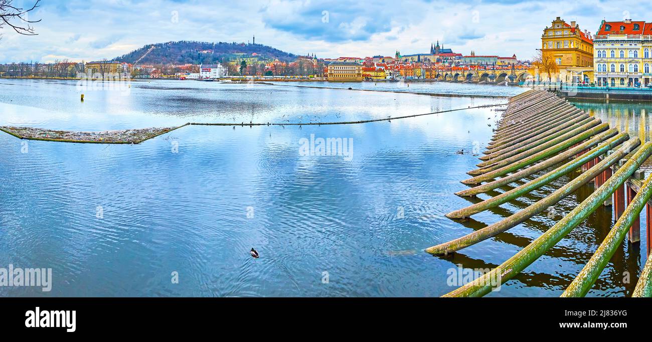 Panorama of Vltava River from the Smetana Embankment with a view of wooden barrier Charles Bridge, St Vitus Cathedral and Petrin Hill in the backgroun Stock Photo
