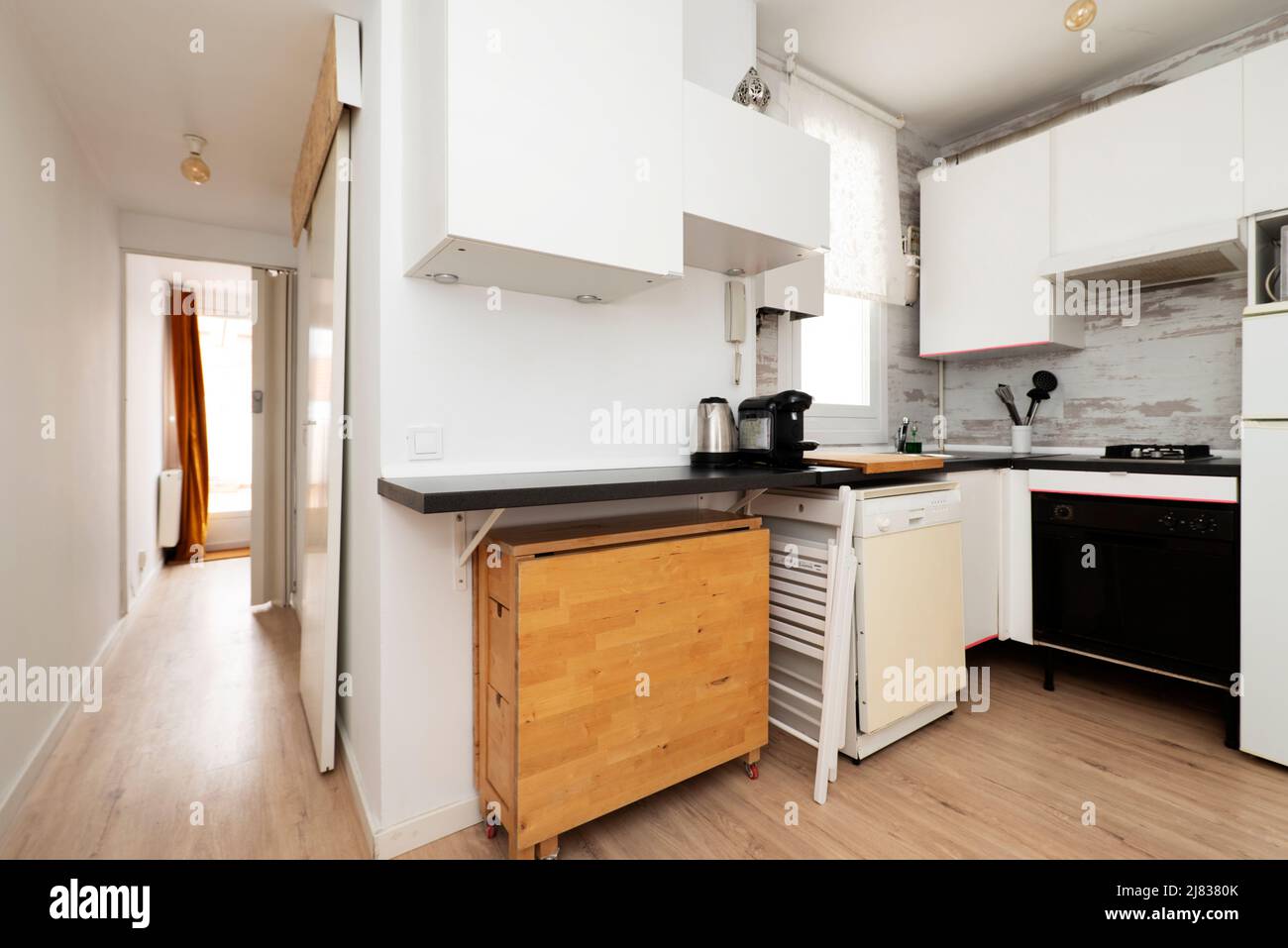 Kitchen with white black countertop and wooden folding dining