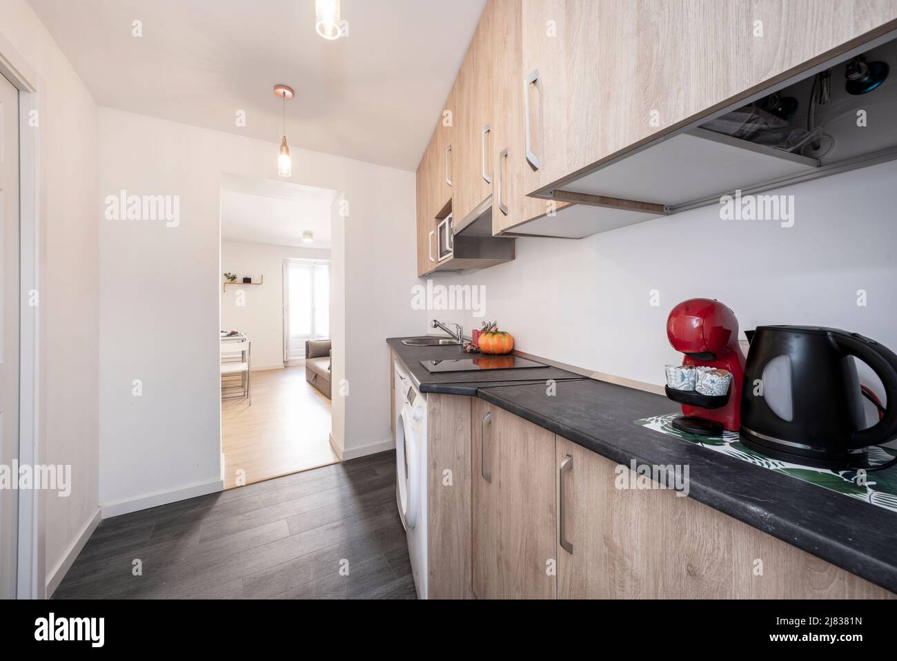 Apartment kitchen with wood cabinets, black countertops, dark tile ...