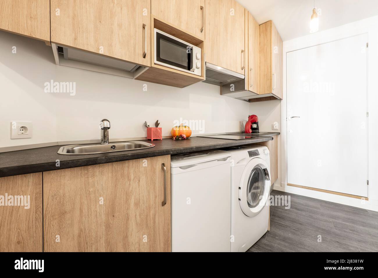Apartment kitchen with wood cabinets, black countertops, dark tile ...