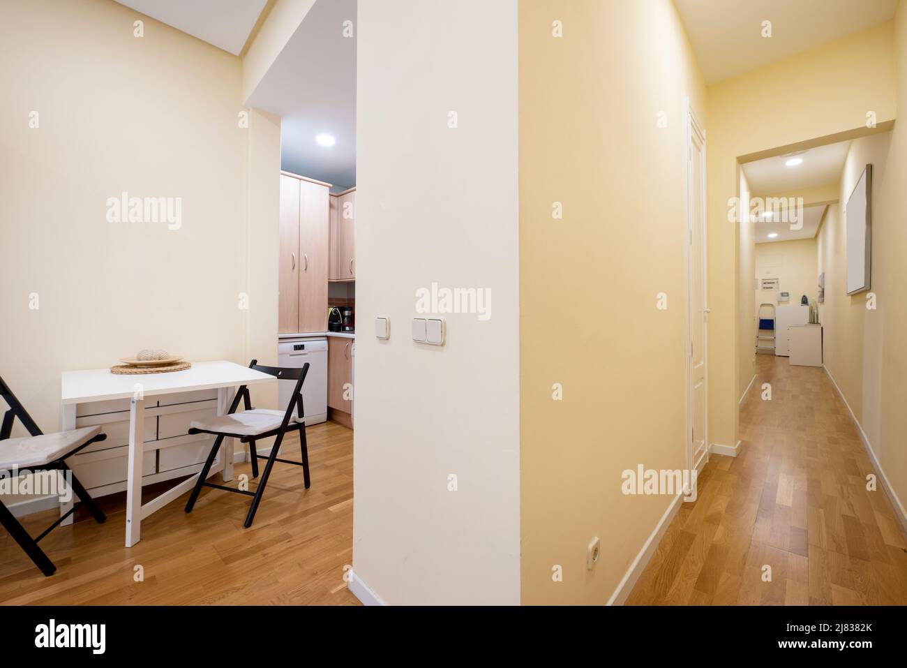 White folding dining table with black chairs at the side of a long