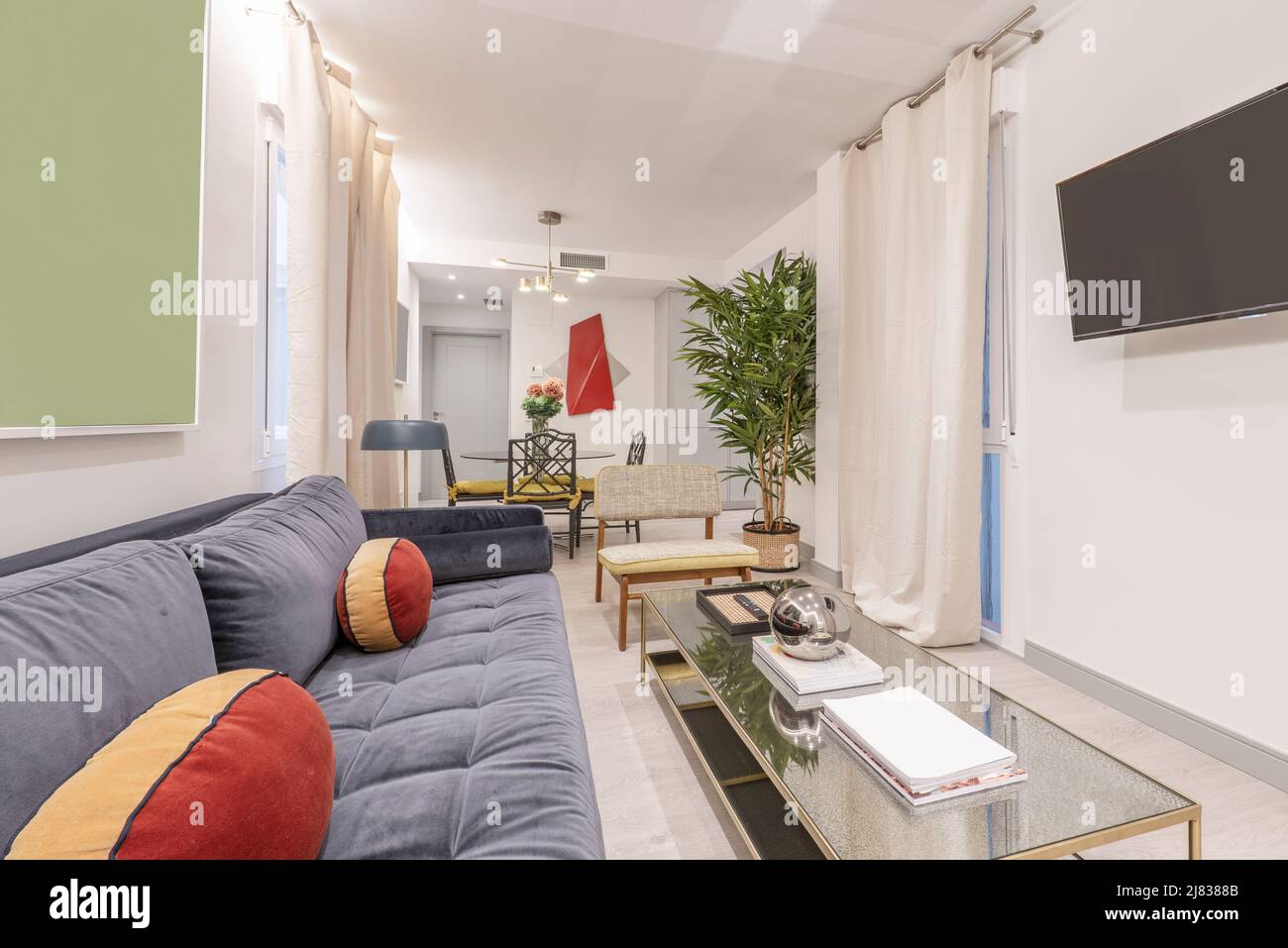Living room with a small glass side table, blue velvet threeseater