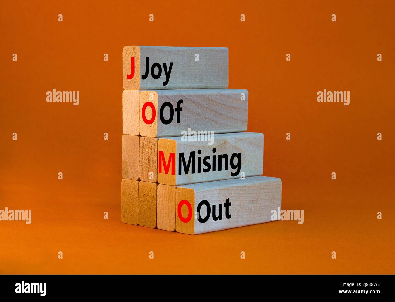JOMO joy of missing out symbol. Concept words JOMO joy of missing out on wooden blocks on beautiful orange table orange background. Business JOMO joy Stock Photo