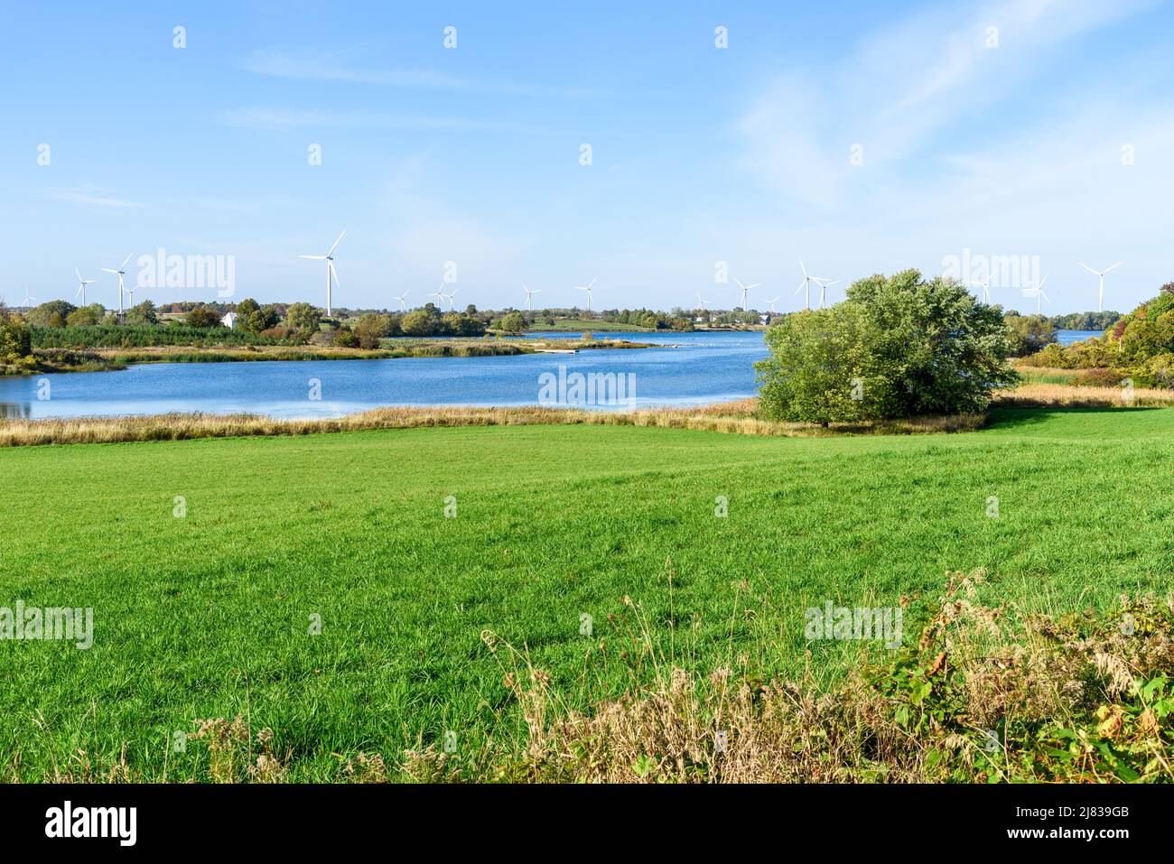 Wind turbines in a idyllic rural landscape on a clear autumn day. A river is in foreground. Stock Photo