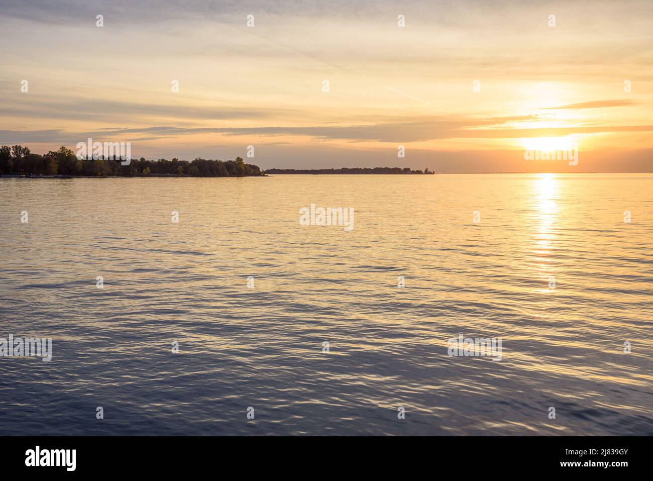 Beautiful autumn sunset over a lake. An island dotted with wind turbines in visible on horizon. Tranquil scene. Lake Ontario, Canada. Stock Photo