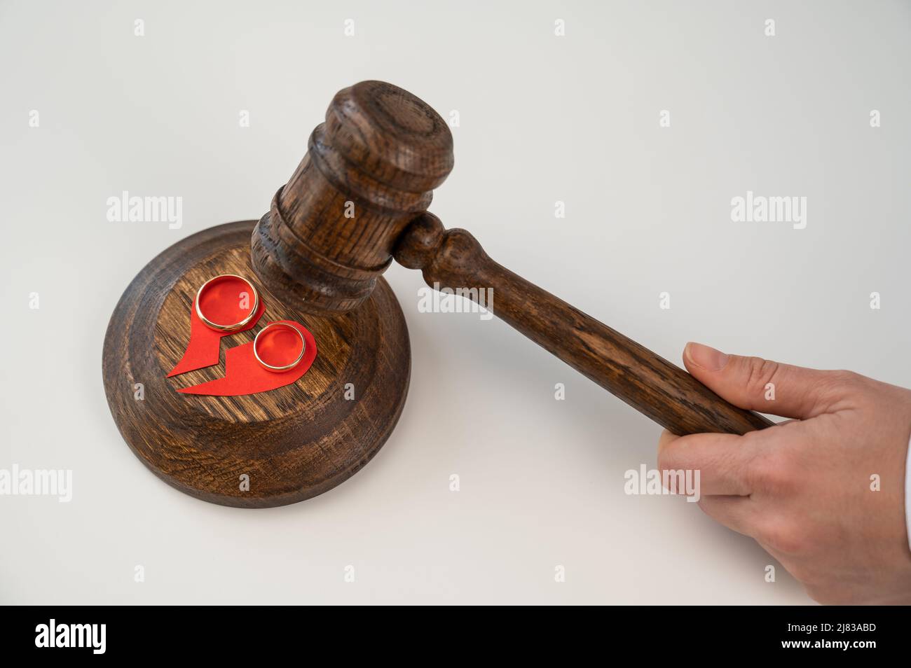 The judge hits the gavel on a broken heart and wedding rings Stock