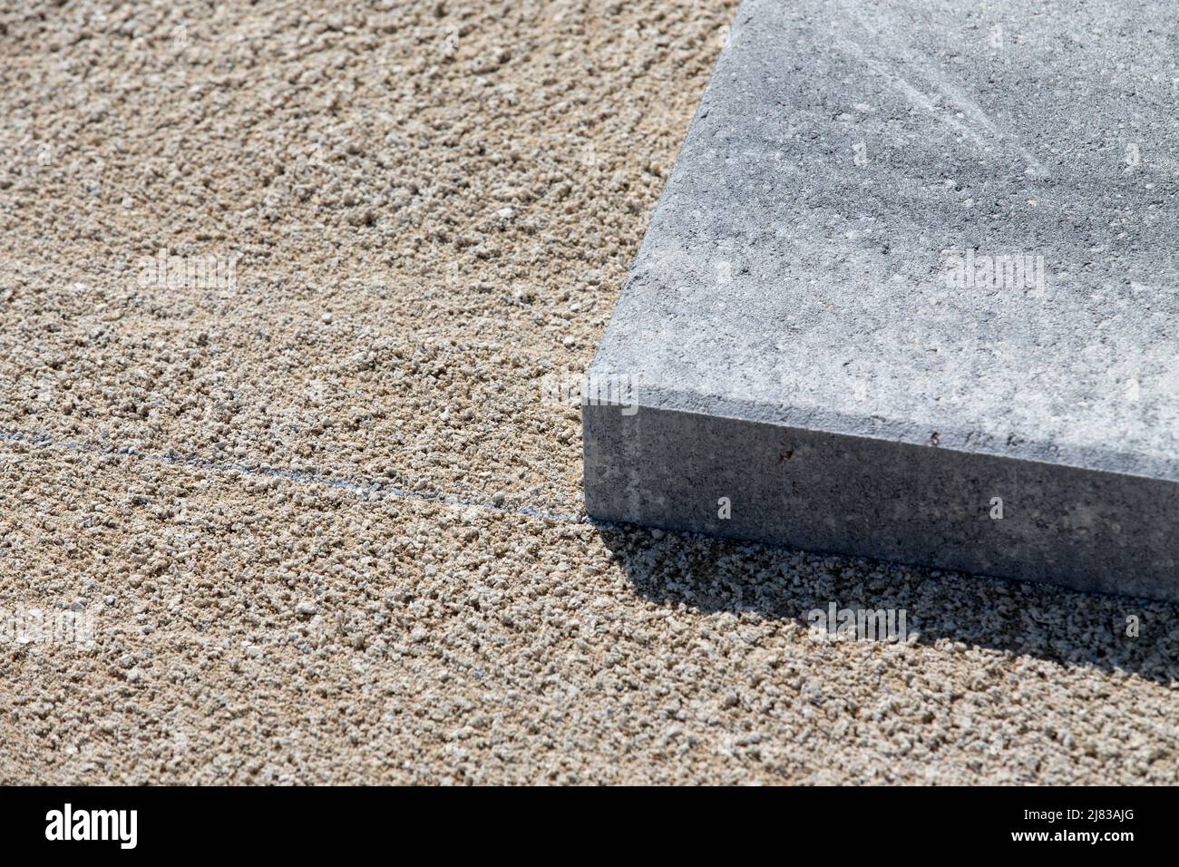 A paving stone or paving brick, set in place on a sand prepared surface. Stock Photo
