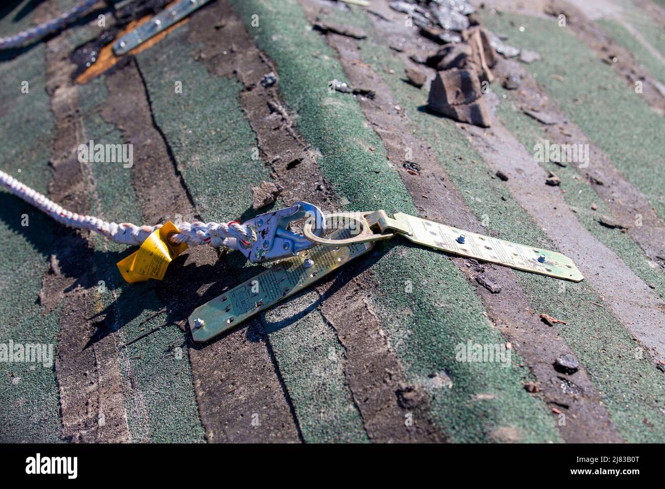 roofer attached via osha safety harness to the saddle of the roof by a hinge clamp. Stock Photo