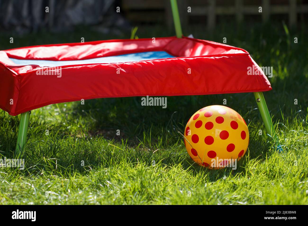 Child's trampoline and ball in a home garden setting Stock Photo