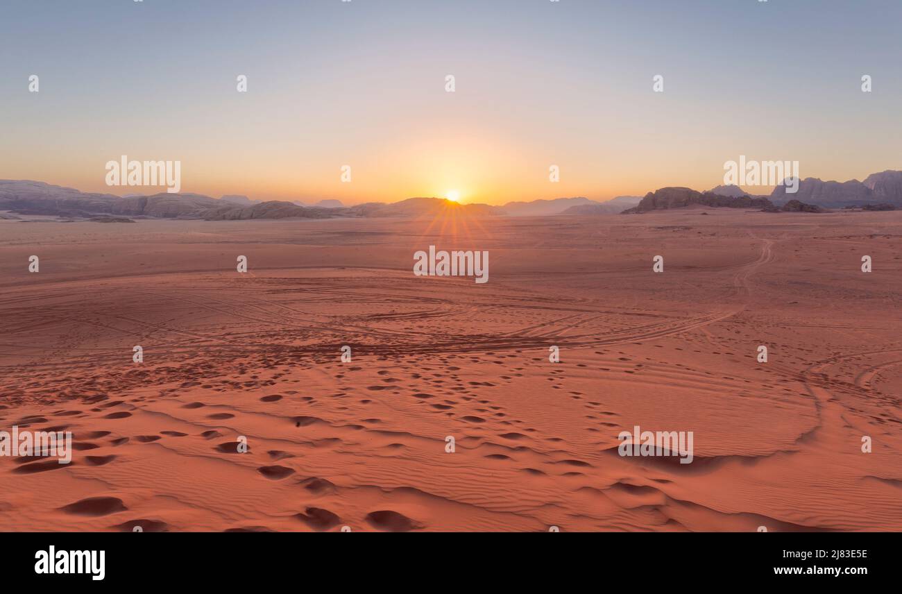 Panoramic view overlooking the red sand desert and Bedouin camp as seen with a cloudy golden sunset in Wadi Rum, Jordan Stock Photo
