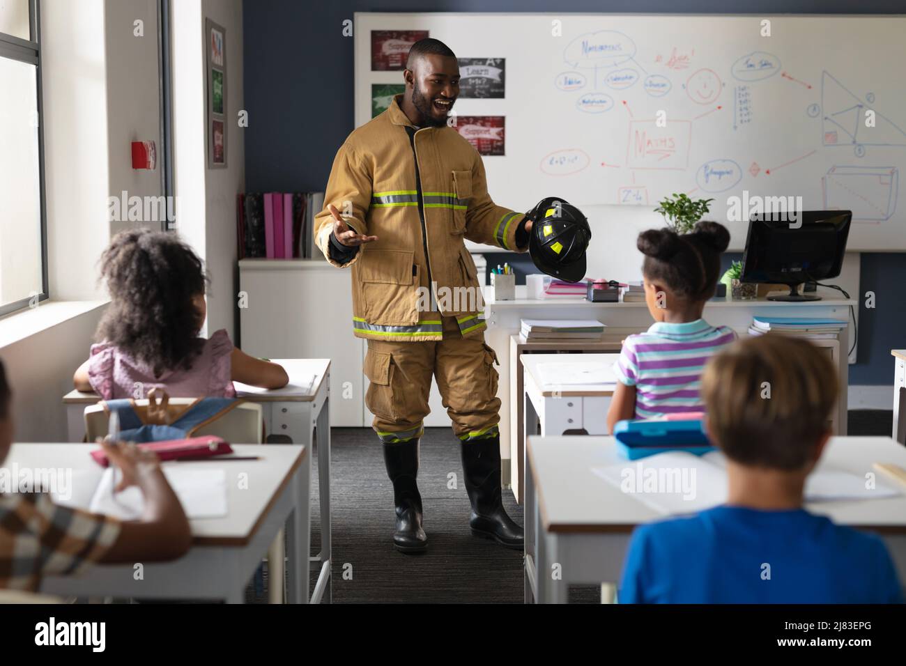 African american young male teacher in firefighter uniform teaching multiracial elementary students Stock Photo