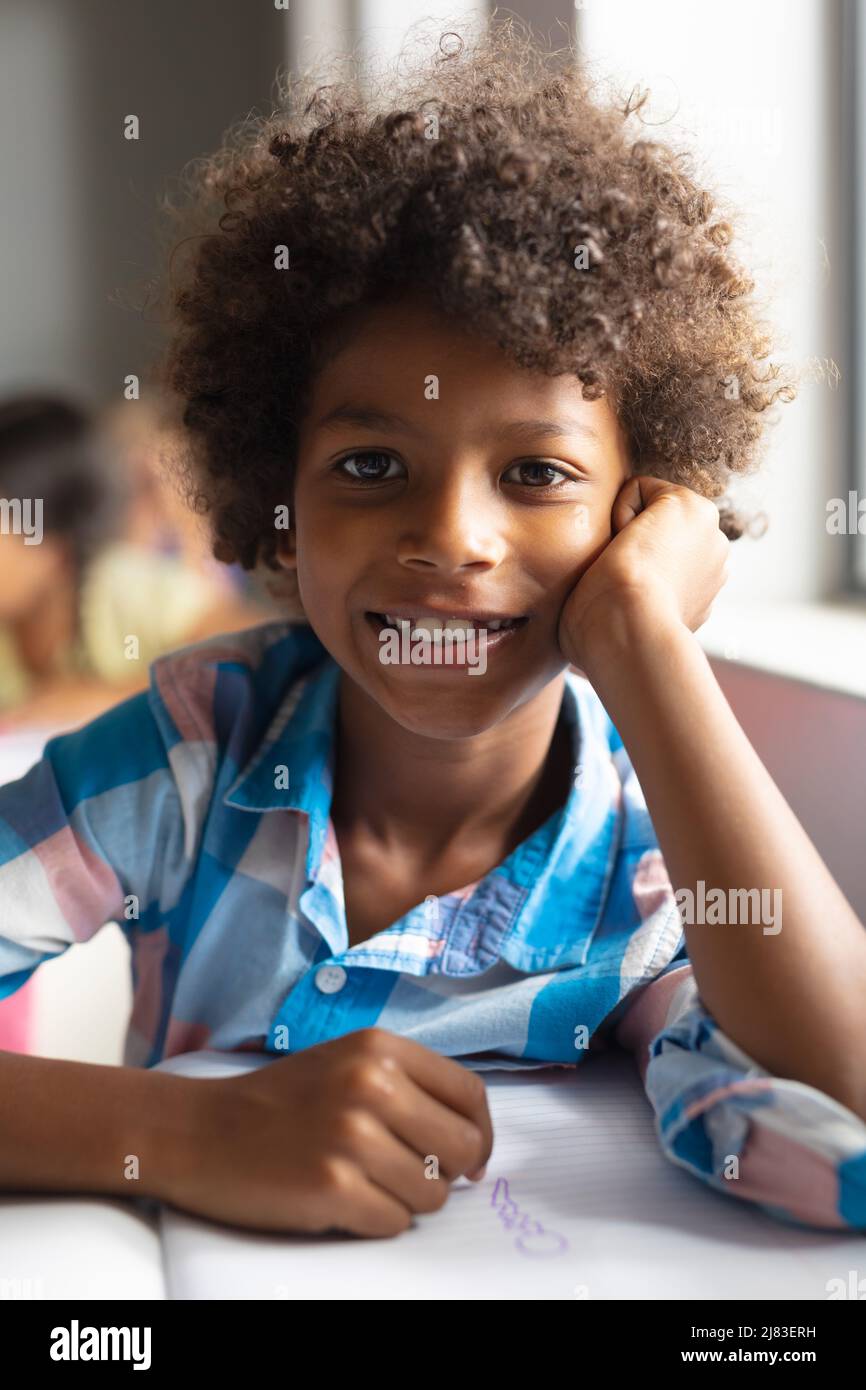 Portrait of smiling african american elementary boy with curly hair sitting  at desk in classroom Stock Photo - Alamy